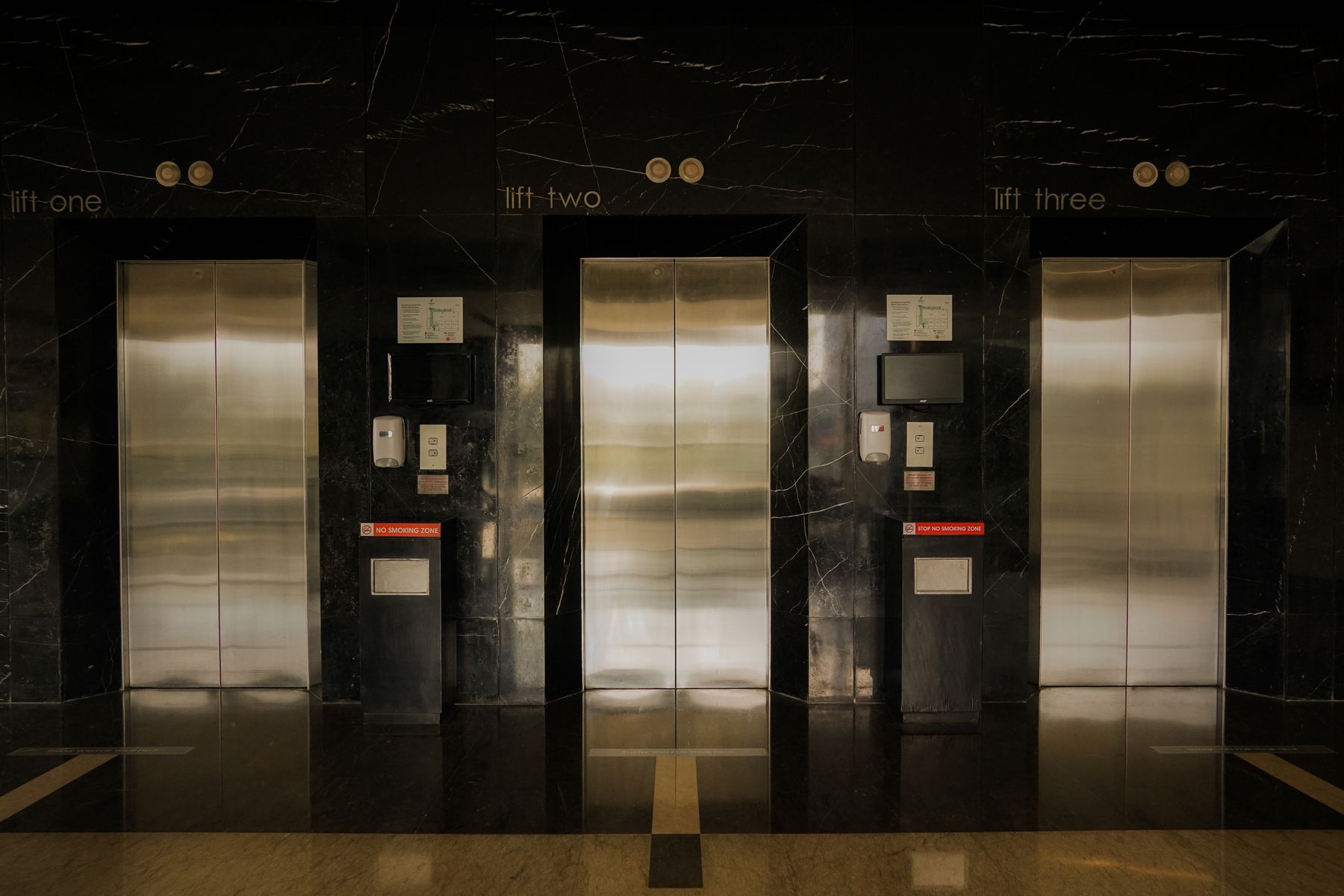 Three commercial elevator doors in a hotel lobby